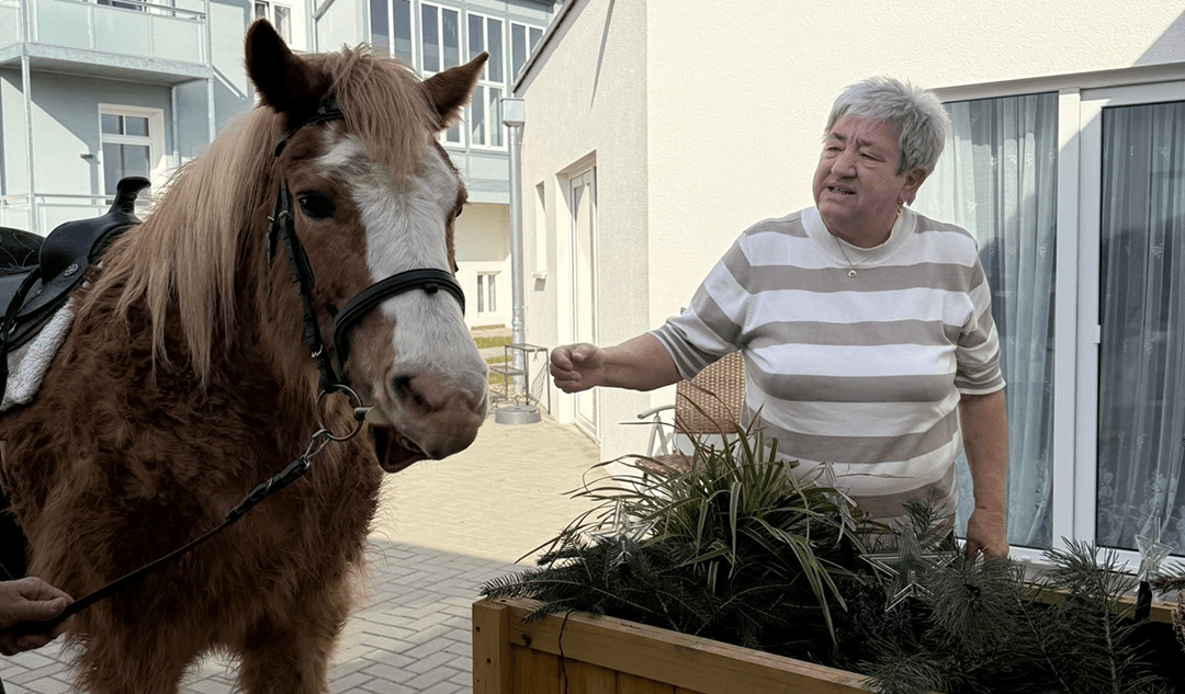 Bewohnerin Frau Adam freut sich über den tierischen Besuch im Wohnpark Bad Suderode. Foto: Humanas